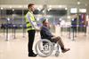 Assitance,Worker,Helping,A,Male,Passenger,In,A,Wheelchair,At