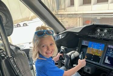 Child participating in United Airlines Make More Wishes programme seated in aircraft cockpit during immersive airport experience