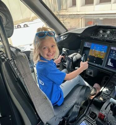 Child participating in United Airlines Make More Wishes programme seated in aircraft cockpit during immersive airport experience